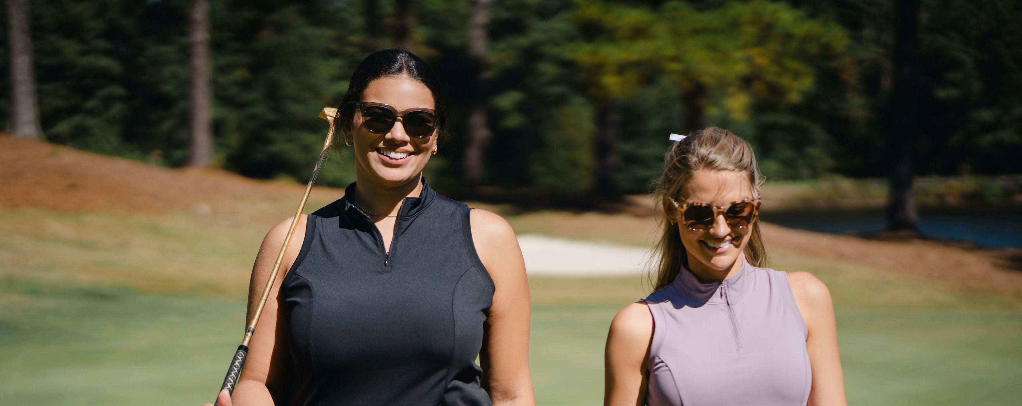 Two female golfers walking off the putting green wearing Harlow Sport The Anywhere Dress